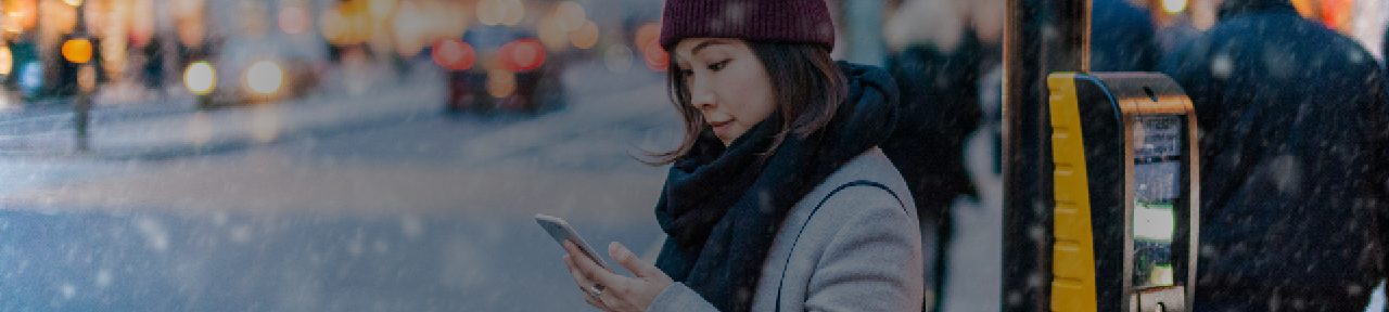 Woman Waiting to Cross Street Looking at Phone